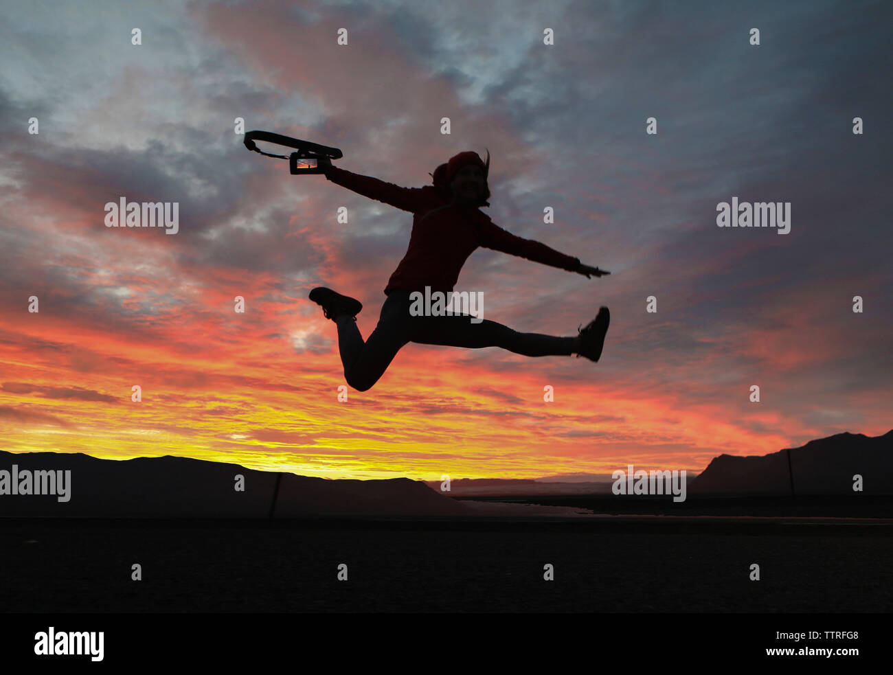 Wanderer, die Kamera, während gegen die drastischen Himmel springen Aufgeregt Stockfoto