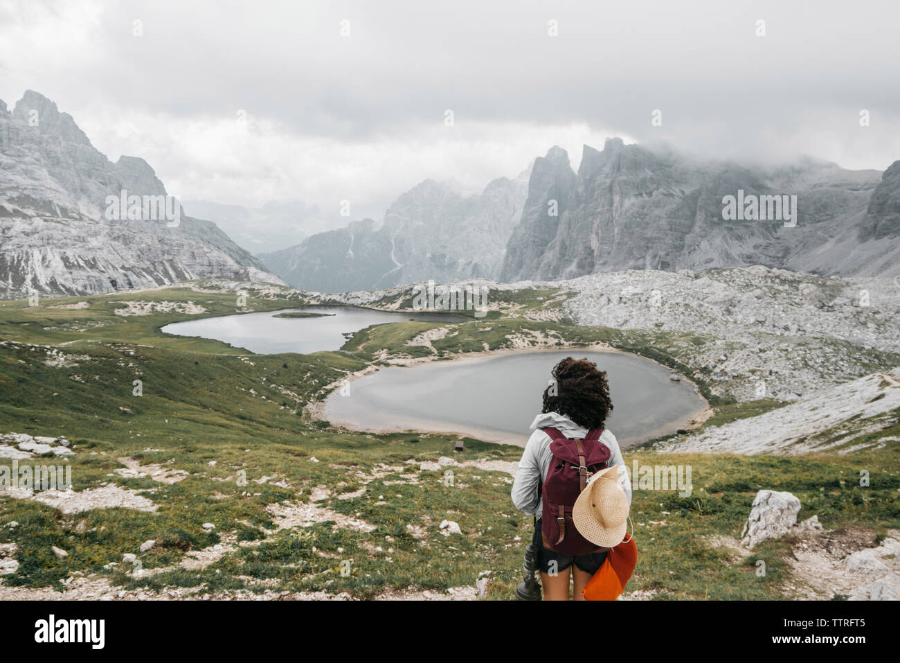 Weibliche Wanderer mit Rucksack auf, während sie gegen die Berge stehen Stockfoto