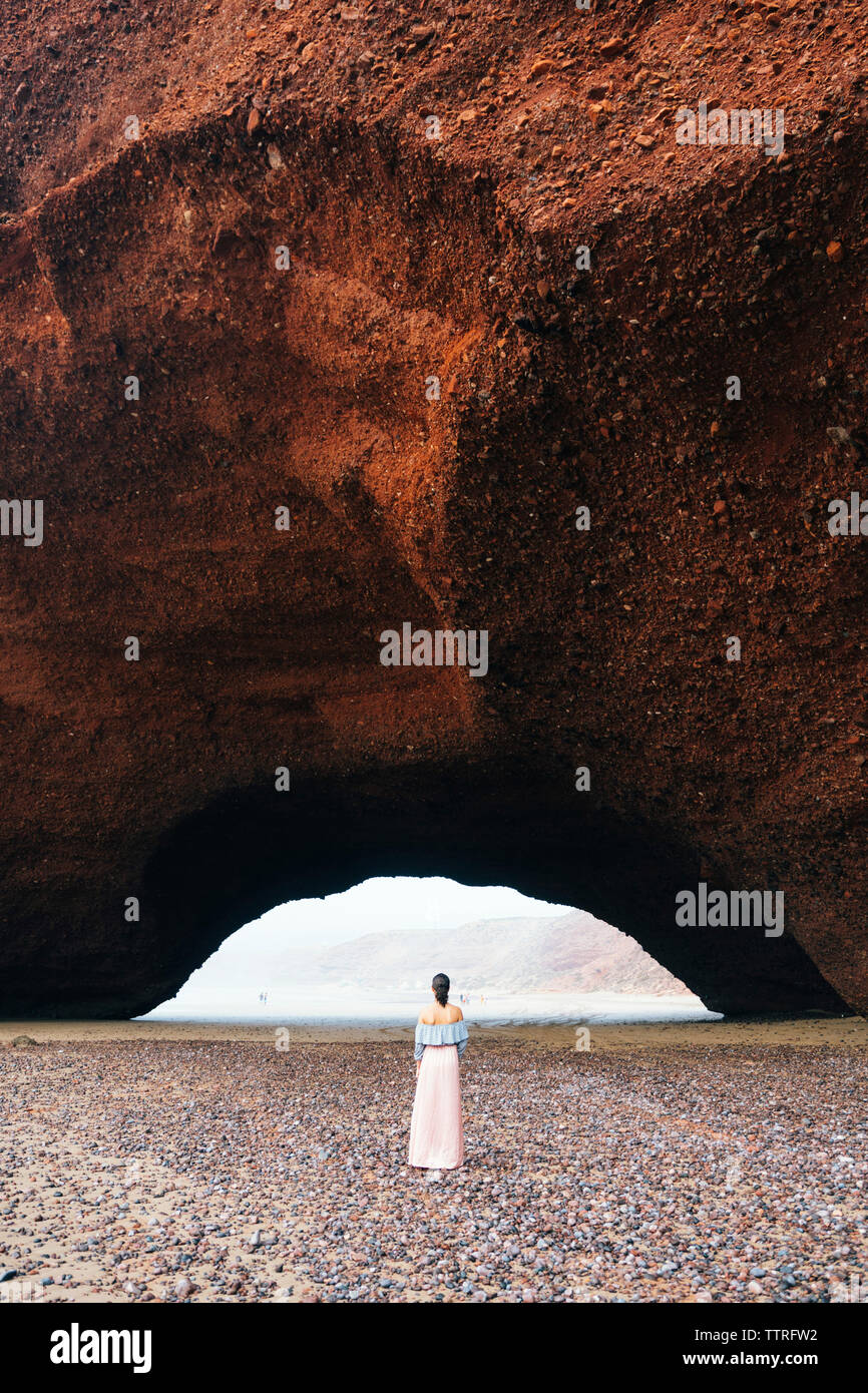 Ansicht der Rückseite stehende Frau auf Sand am Strand von Berg Stockfoto