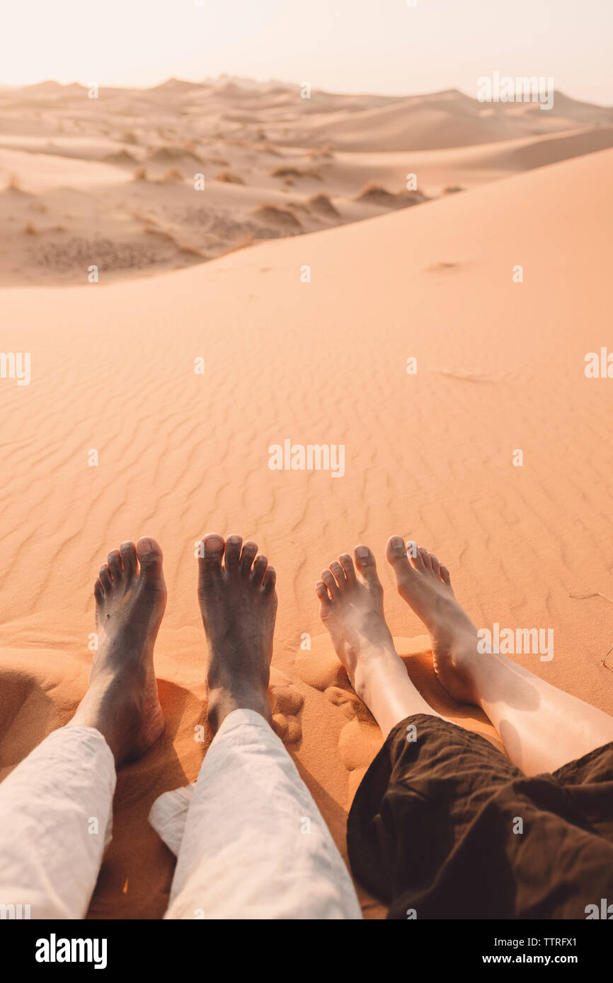 Niedrige Abschnitt von Freunden in der Wüste Sahara sitzen bei Sonnenuntergang Stockfoto