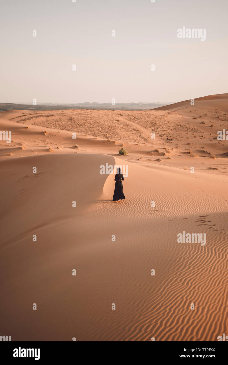 Ansicht der Rückseite Frau wandern in der Sahara gegen den klaren Himmel bei Sonnenuntergang Stockfoto