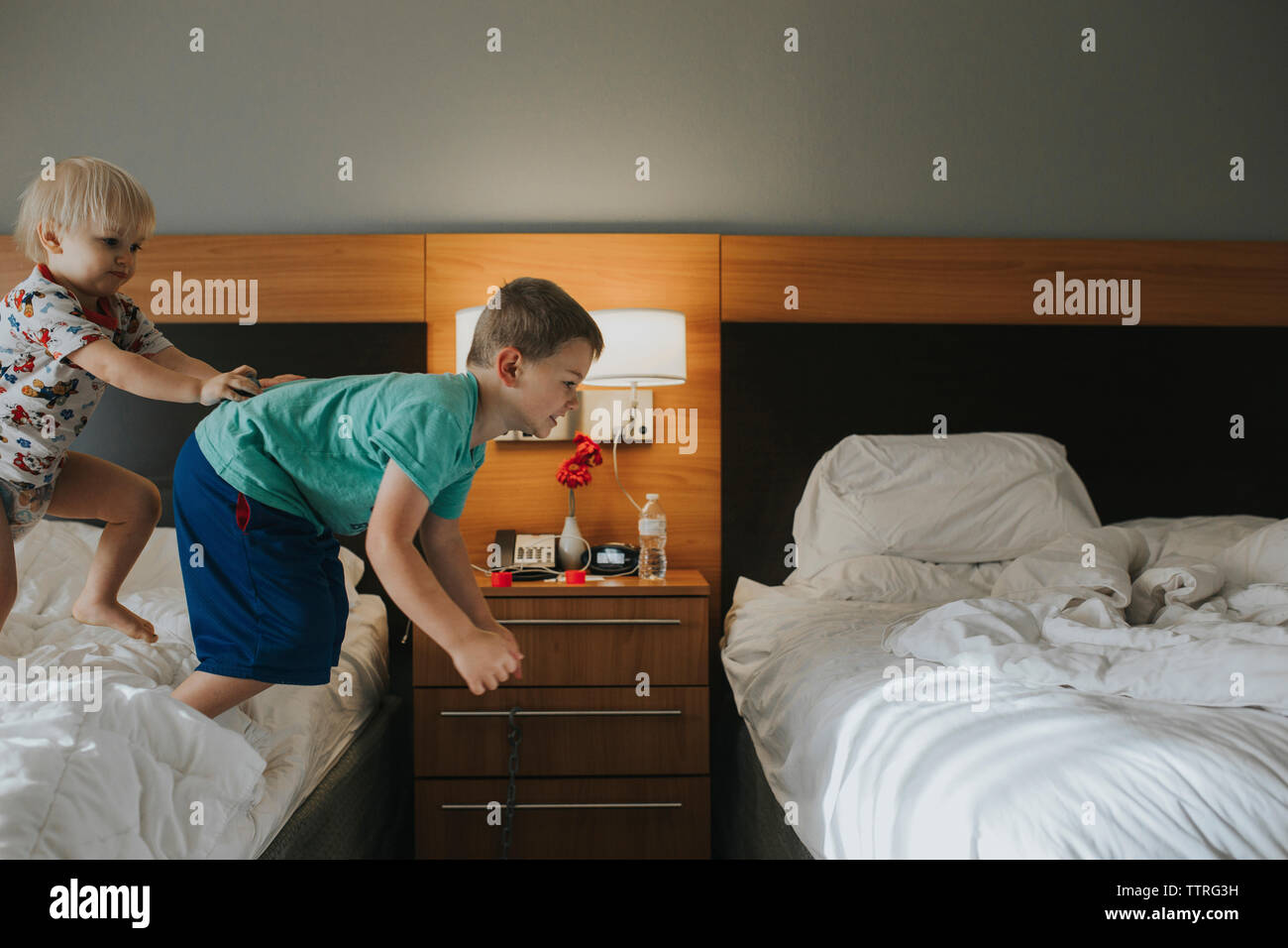 Junge, Bruder von Bett zu Hause springen Stockfoto