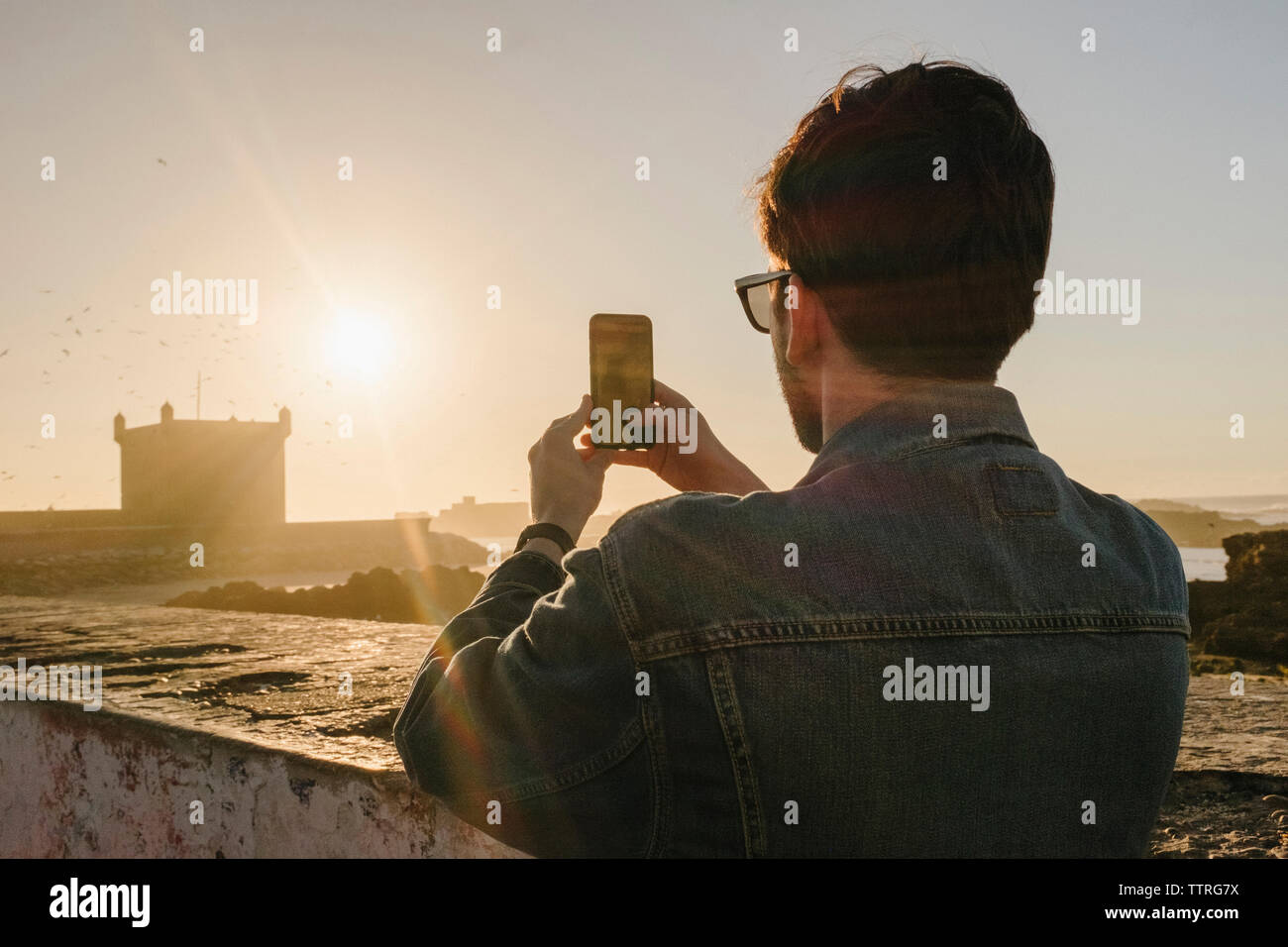 Rückansicht des Menschen fotografieren mit Handy vor klaren Himmel bei Sonnenuntergang Stockfoto