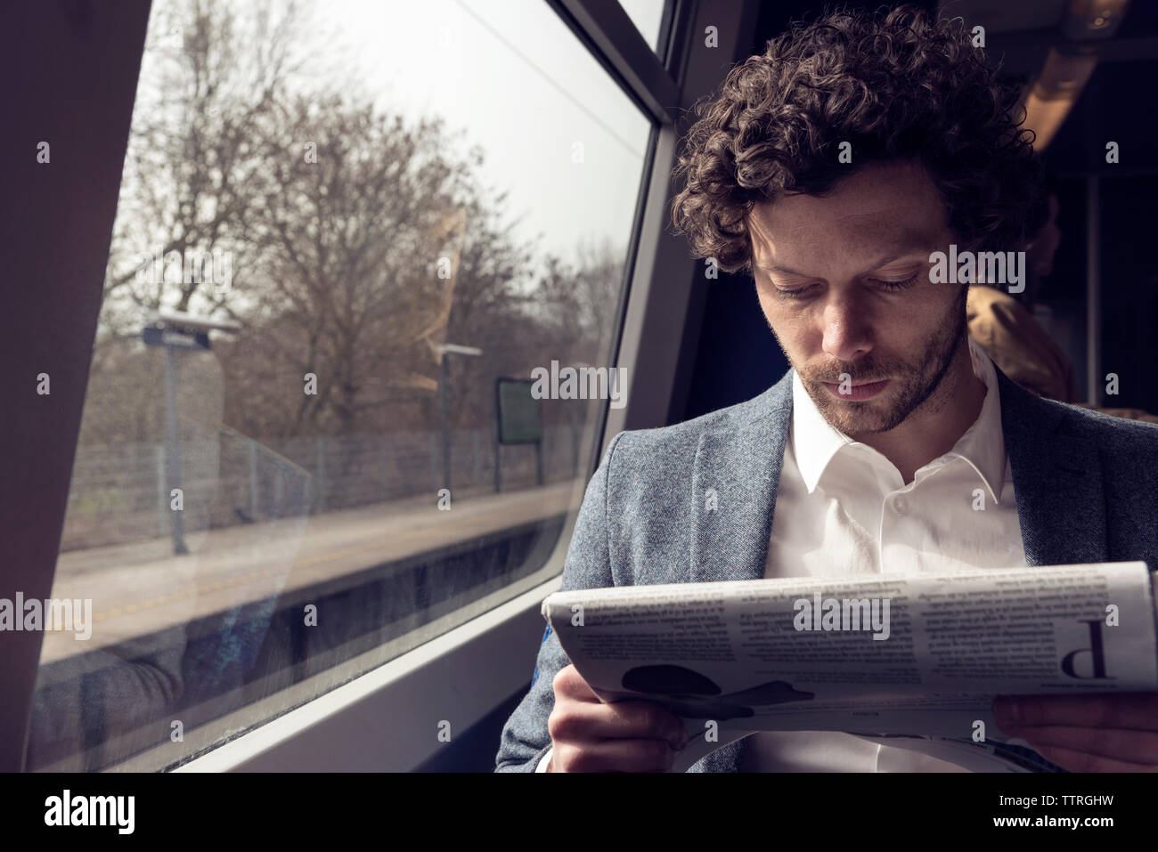 Geschäftsmann liest Zeitung im Zug Stockfoto