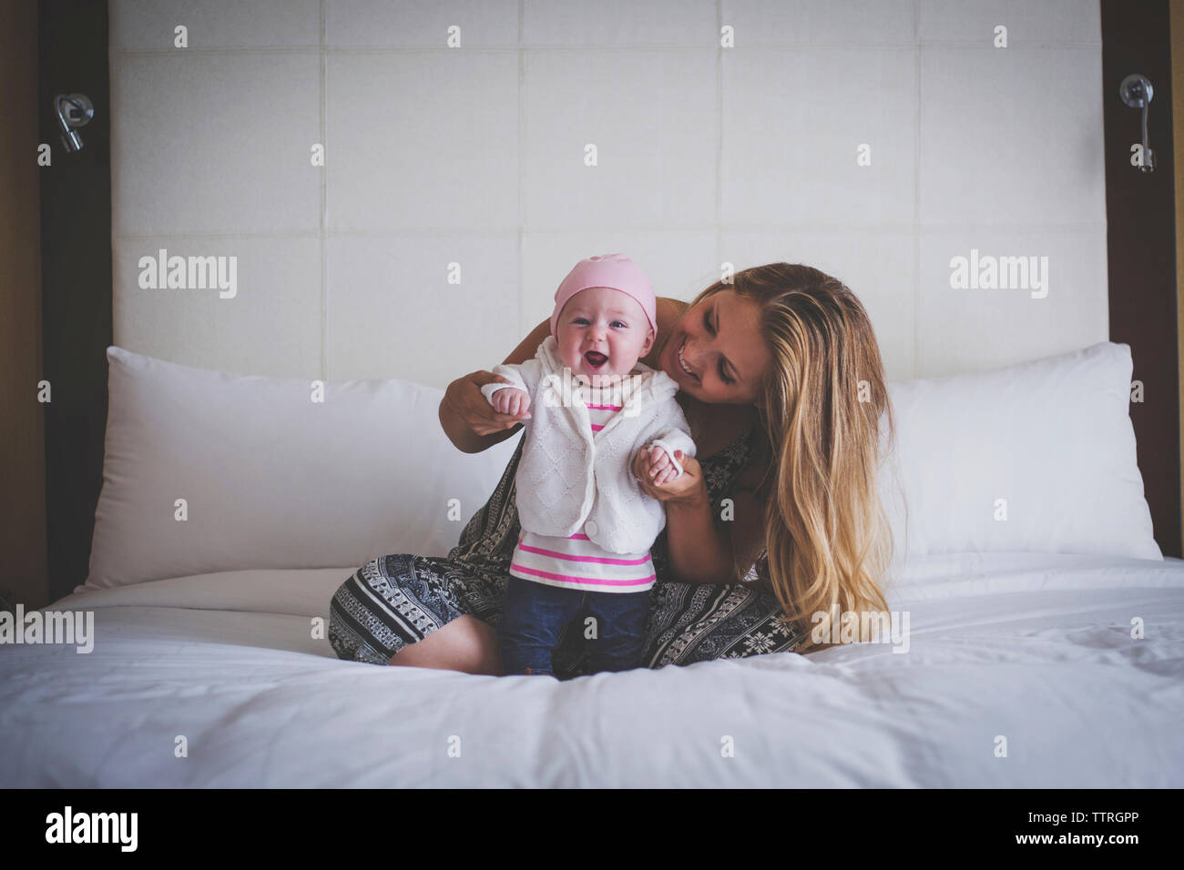 Mutter Unterstützung Baby steht auf Bett zu Hause Stockfoto