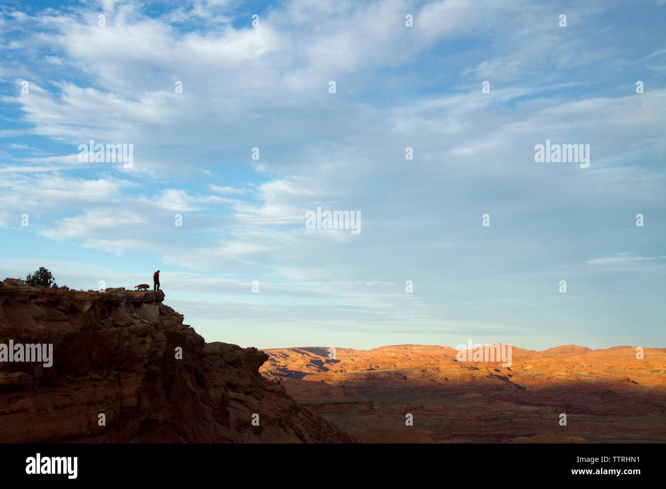 Fernsicht auf silhouette Wanderer mit Hund steht an der Spitze des Berges gegen bewölkter Himmel Stockfoto