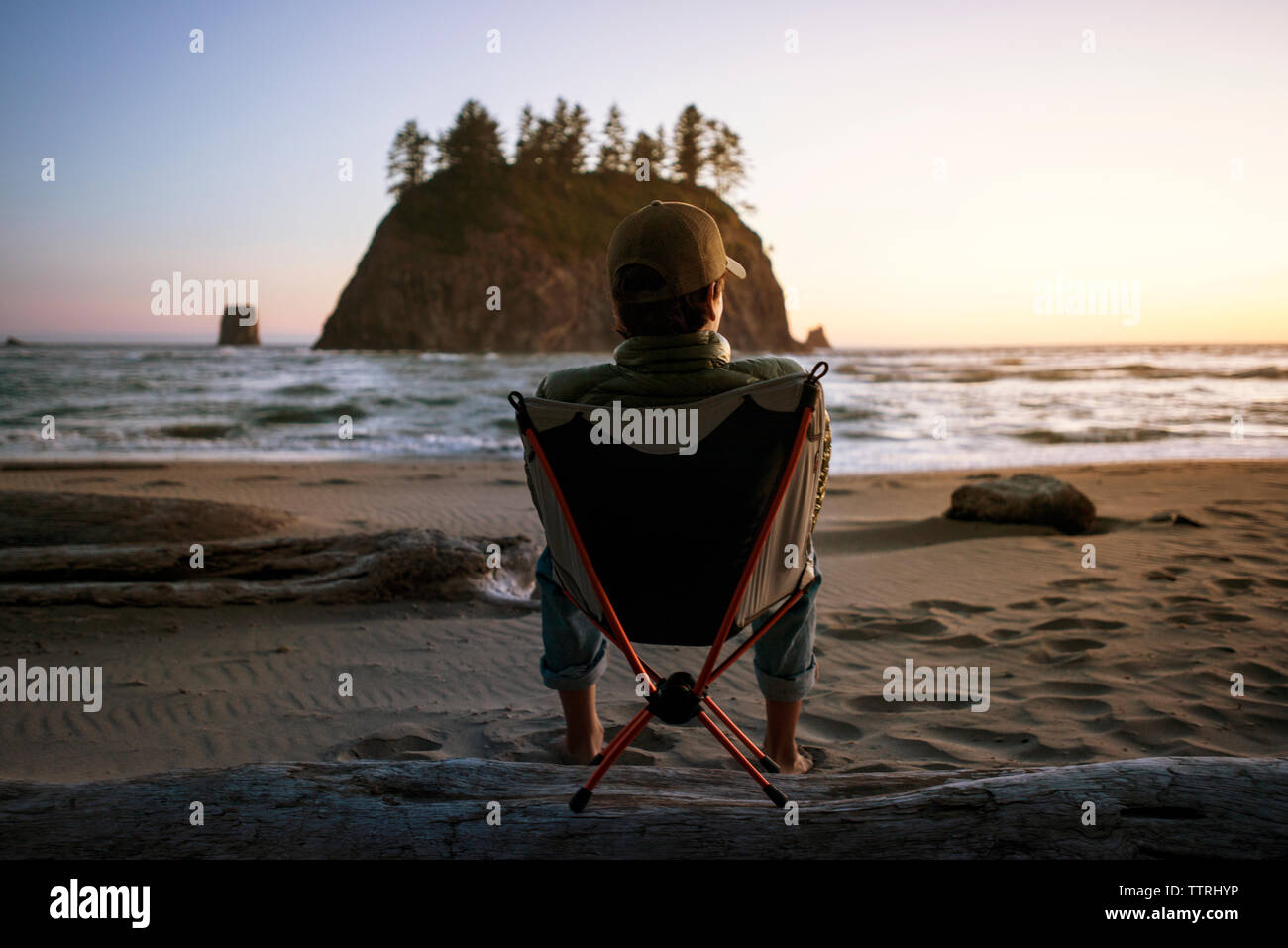 Ansicht der Rückseite des Teenager sitzen auf Liegestuhl am Strand bei Sonnenuntergang Stockfoto