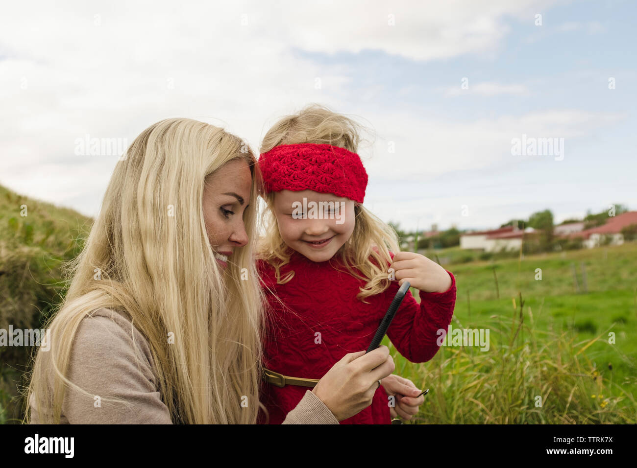 Glückliche Mutter und Tochter auf der Suche nach Smart Phone auf dem Feld Stockfoto