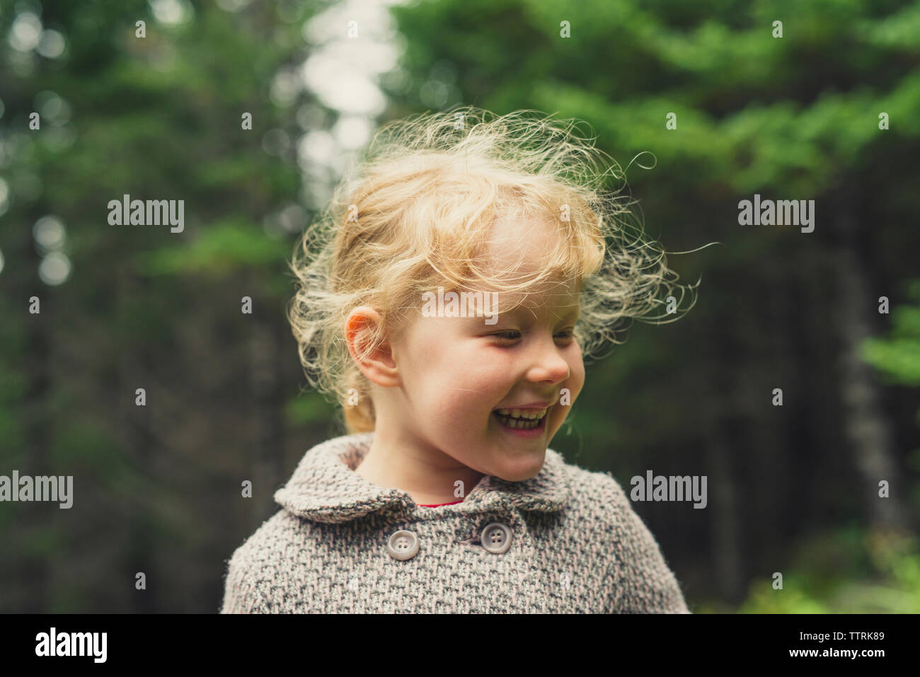 Fröhliches Mädchen mit blonden Haaren im Wald Stockfoto