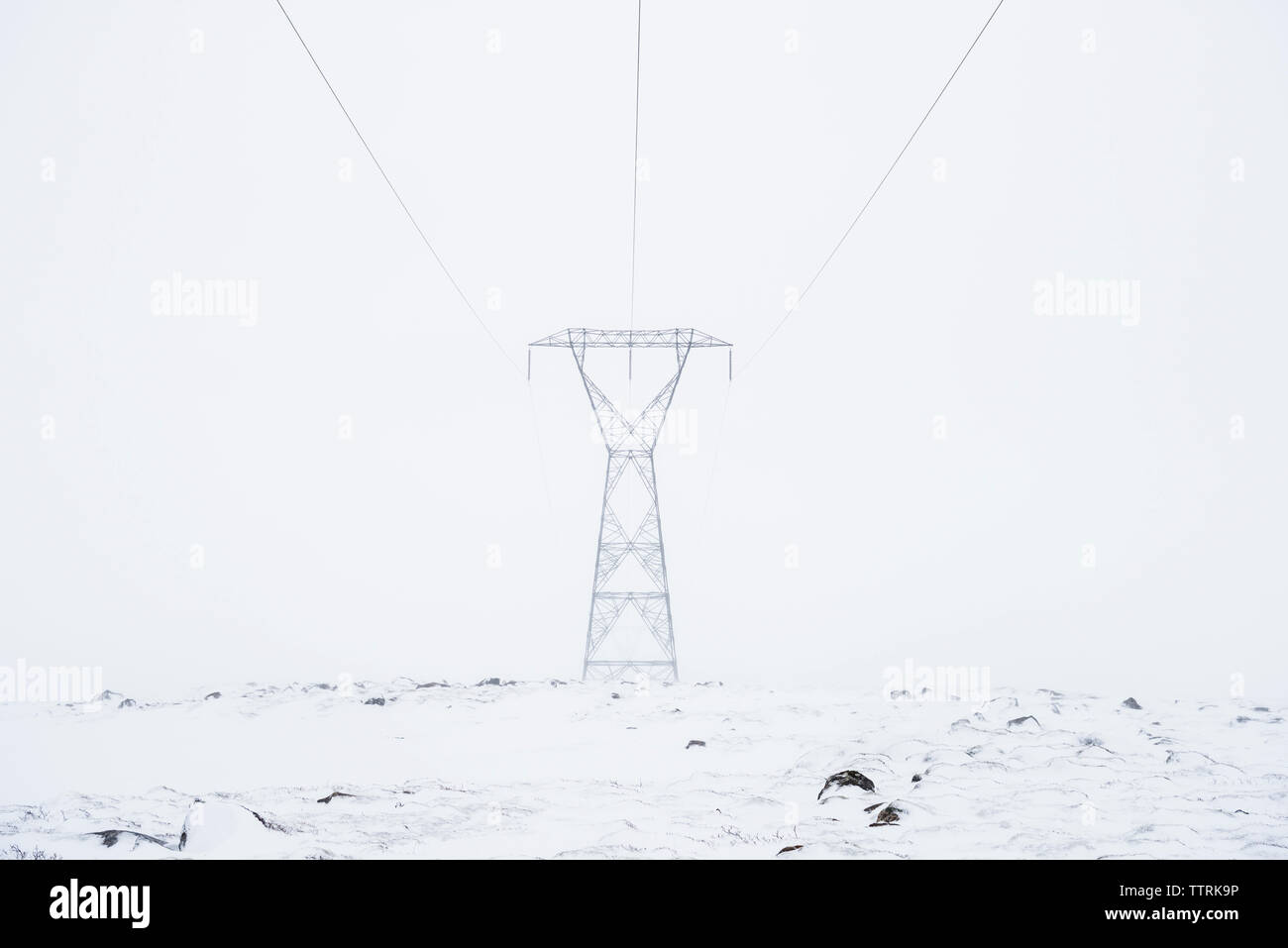 Strom pylon auf schneebedeckten Feld gegen den klaren Himmel Stockfoto