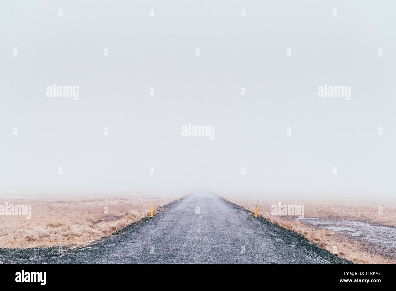 Country Road inmitten gegen den klaren Himmel während der nebligen Wetter Stockfoto