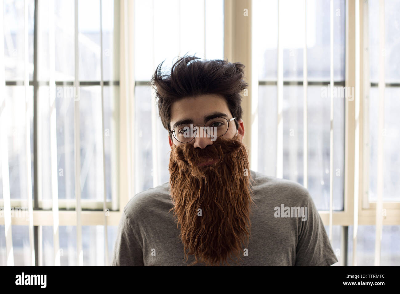 Porträt der Mann mit künstlichen Schnurrbart und Bart zu Hause Stockfoto