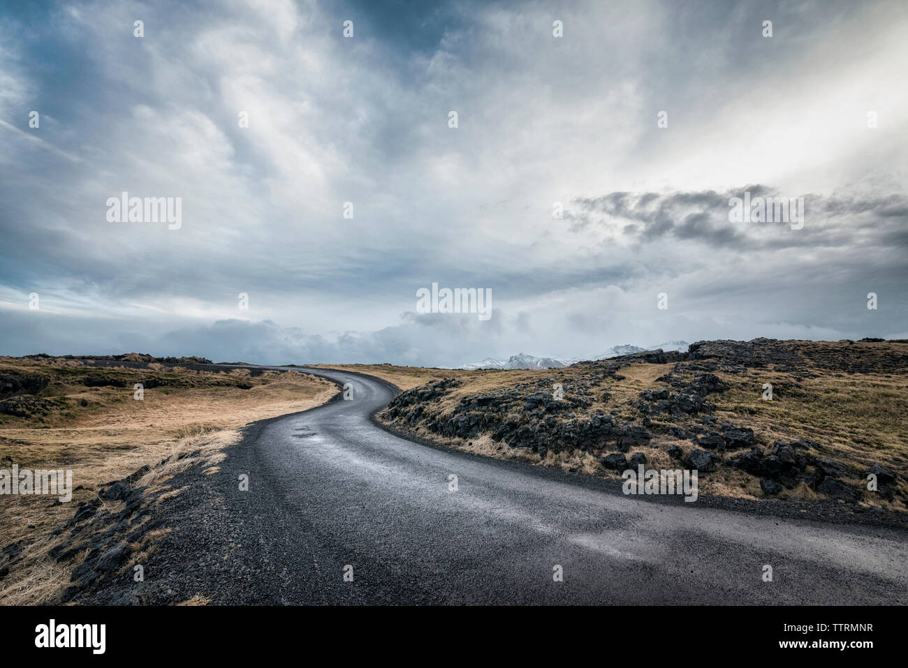 Leere Straße inmitten von Feld gegen bewölkter Himmel Stockfoto