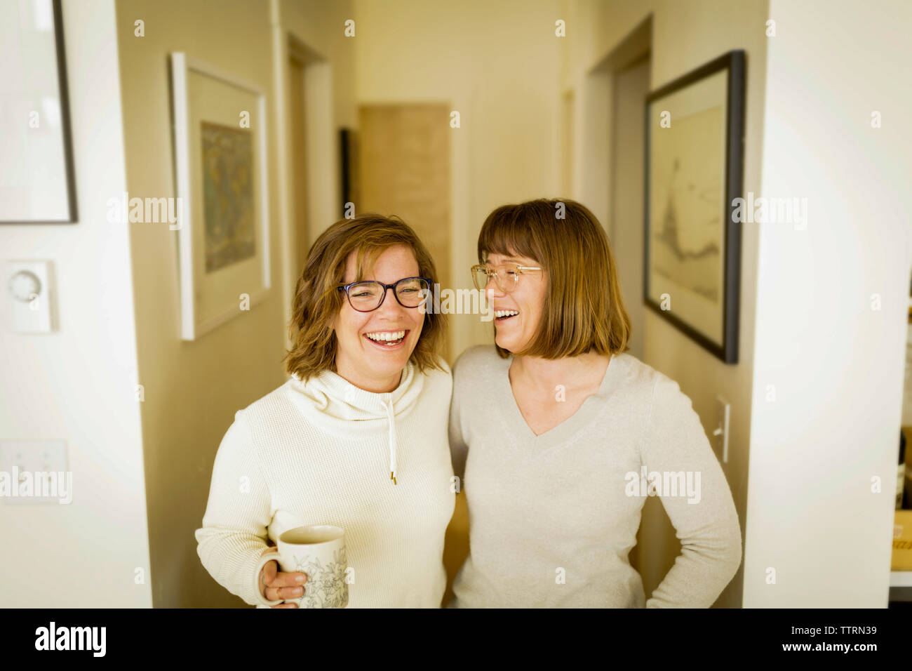 Fröhliche Geschwister im Korridor zu Hause stehend Stockfoto