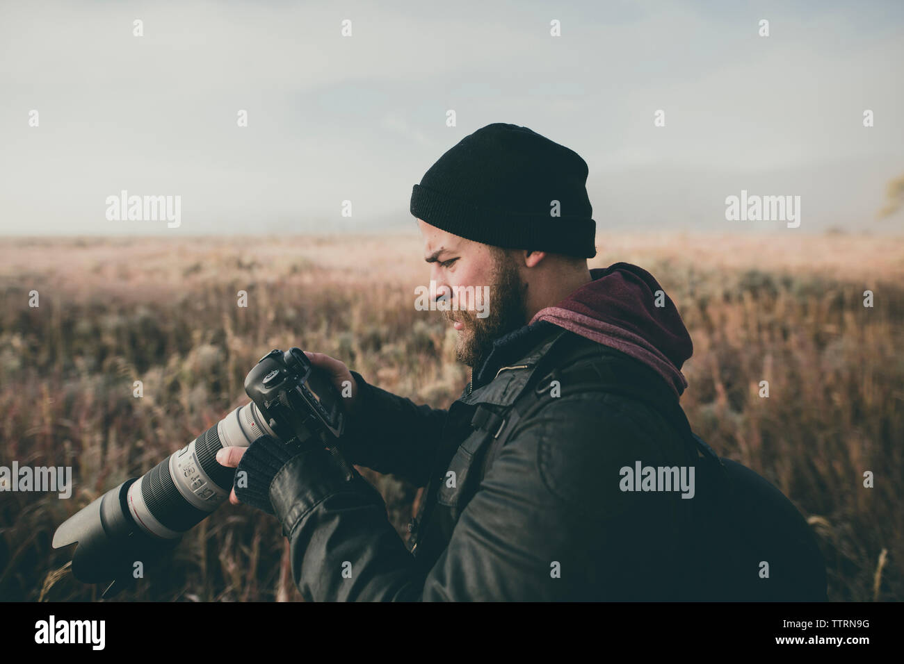 Seitenansicht der Wanderer auf Kamera beim Stehen auf Feld Stockfoto