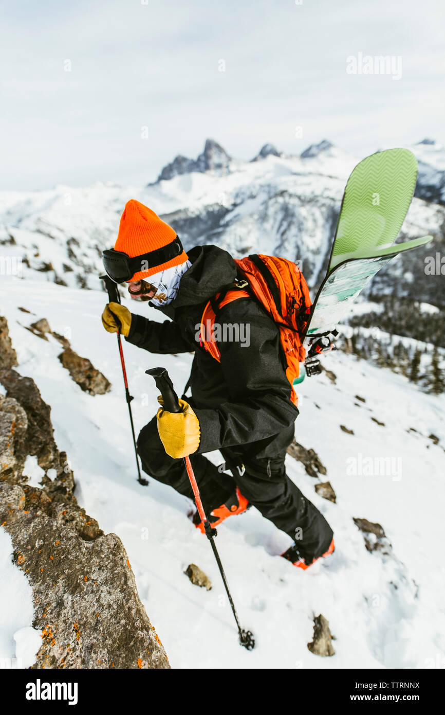 Wanderer mit Rucksack und Skistöcke klettern schneebedeckten Berg Stockfoto