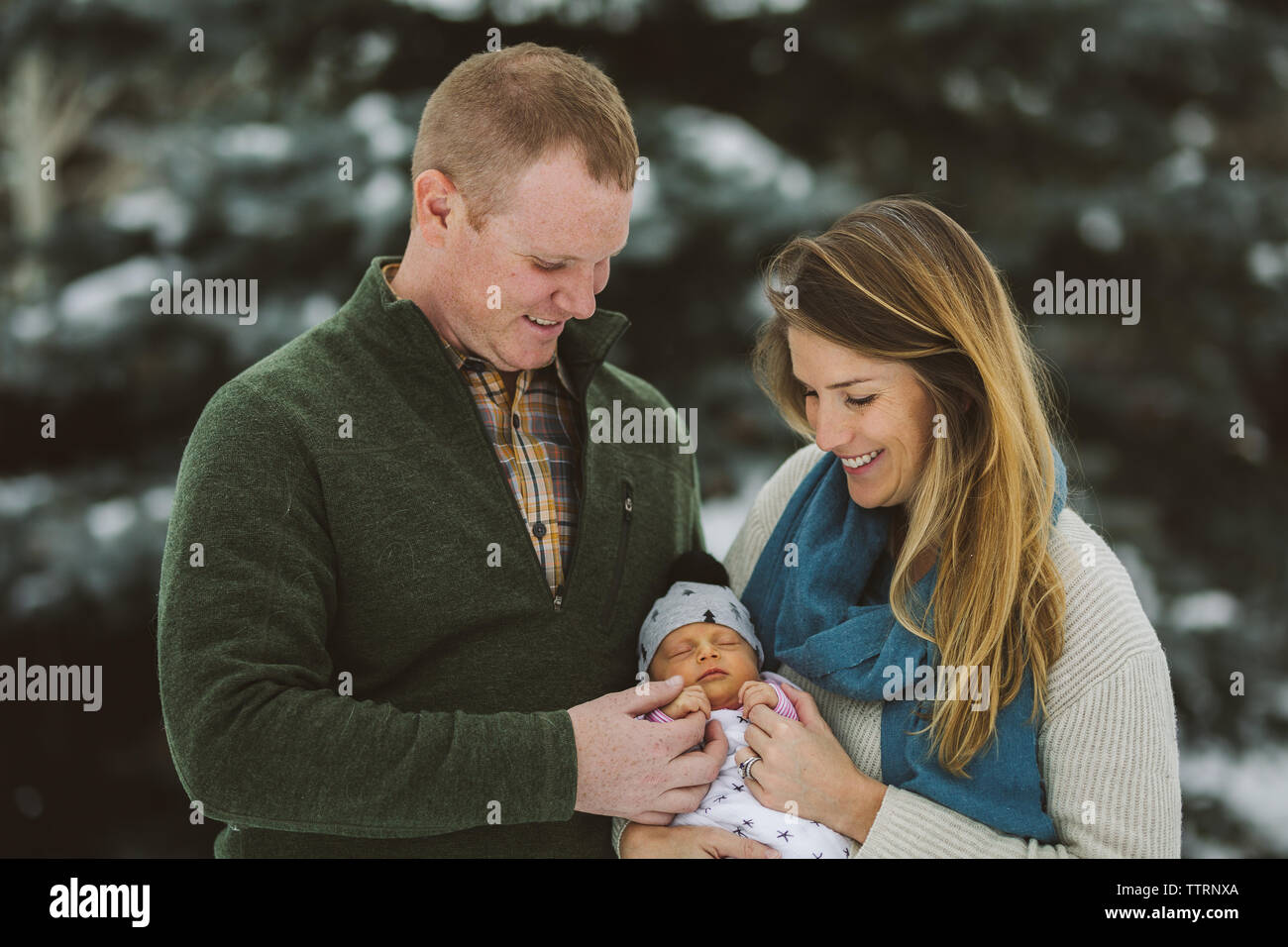 Mama und Papa halten Hand von winzigen neugeborenen Mädchen draußen im Winter Stockfoto