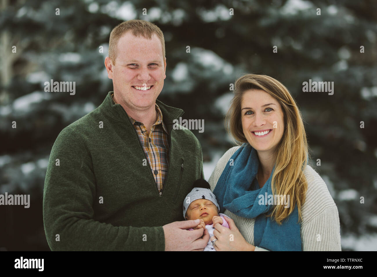 Neue Mutter und Vater halten Hand des neugeborenen Mädchen draußen auf Kamera lächelnd Stockfoto