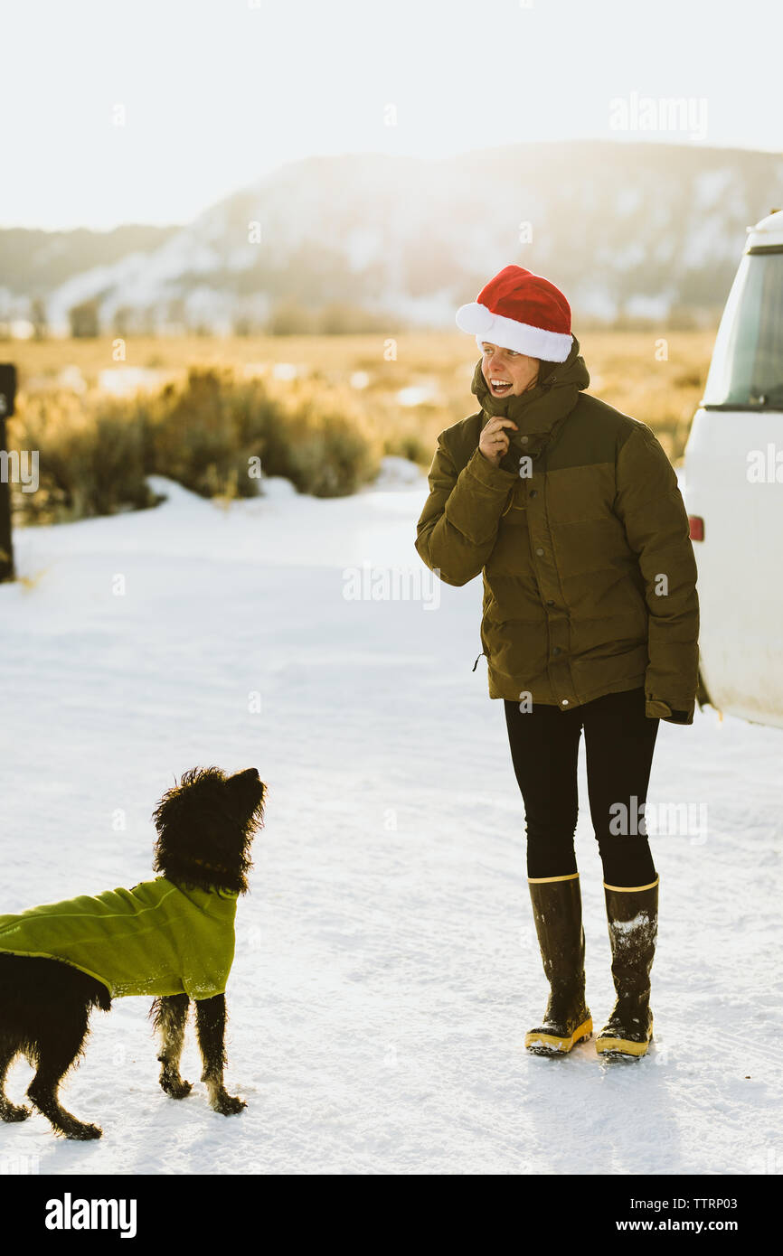 Glückliche junge Dame in santa hut spielt mit schwarzer Welpe Hund Stockfoto