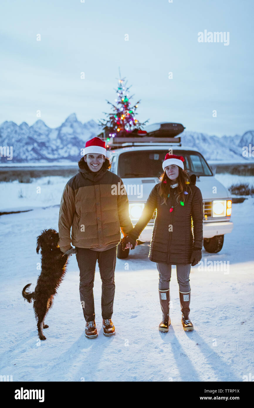 Glückliches Paar halten die Hände vor ihrem Van mit Hund Stockfoto