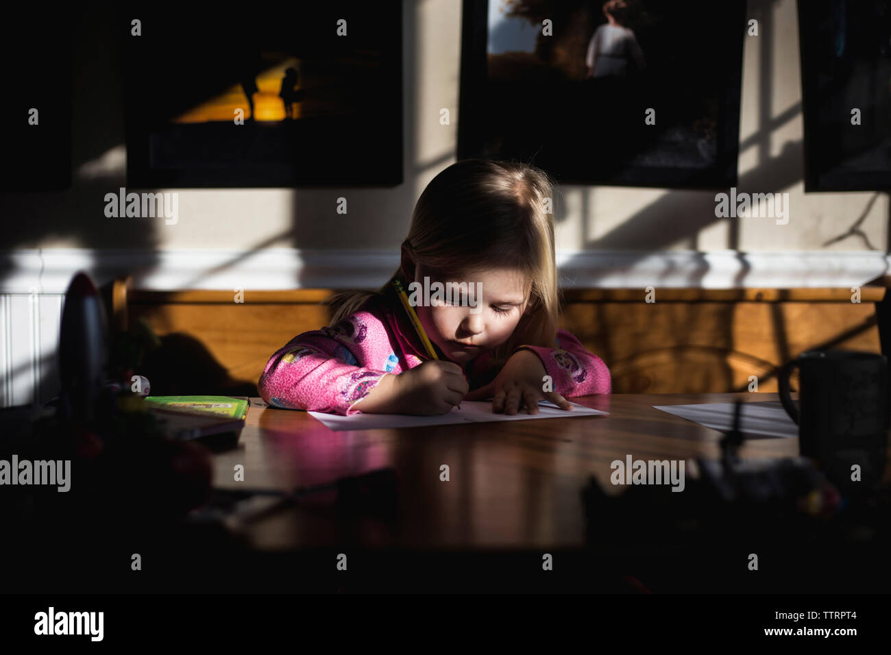 Mädchen schreiben auf Papier am Tisch Stockfoto