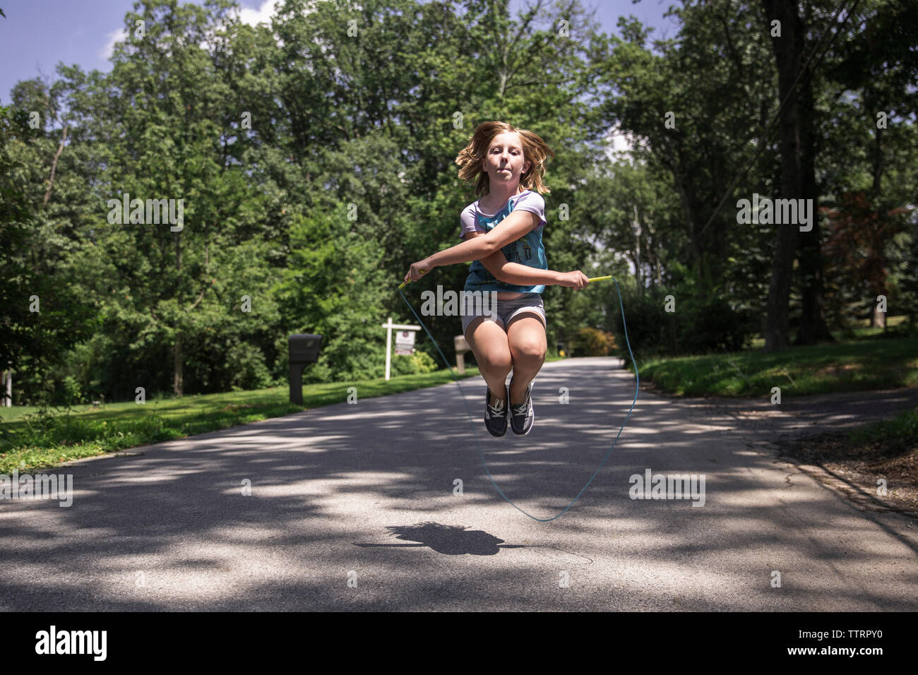 Mädchen Überspringen auf der Straße am Park Stockfoto