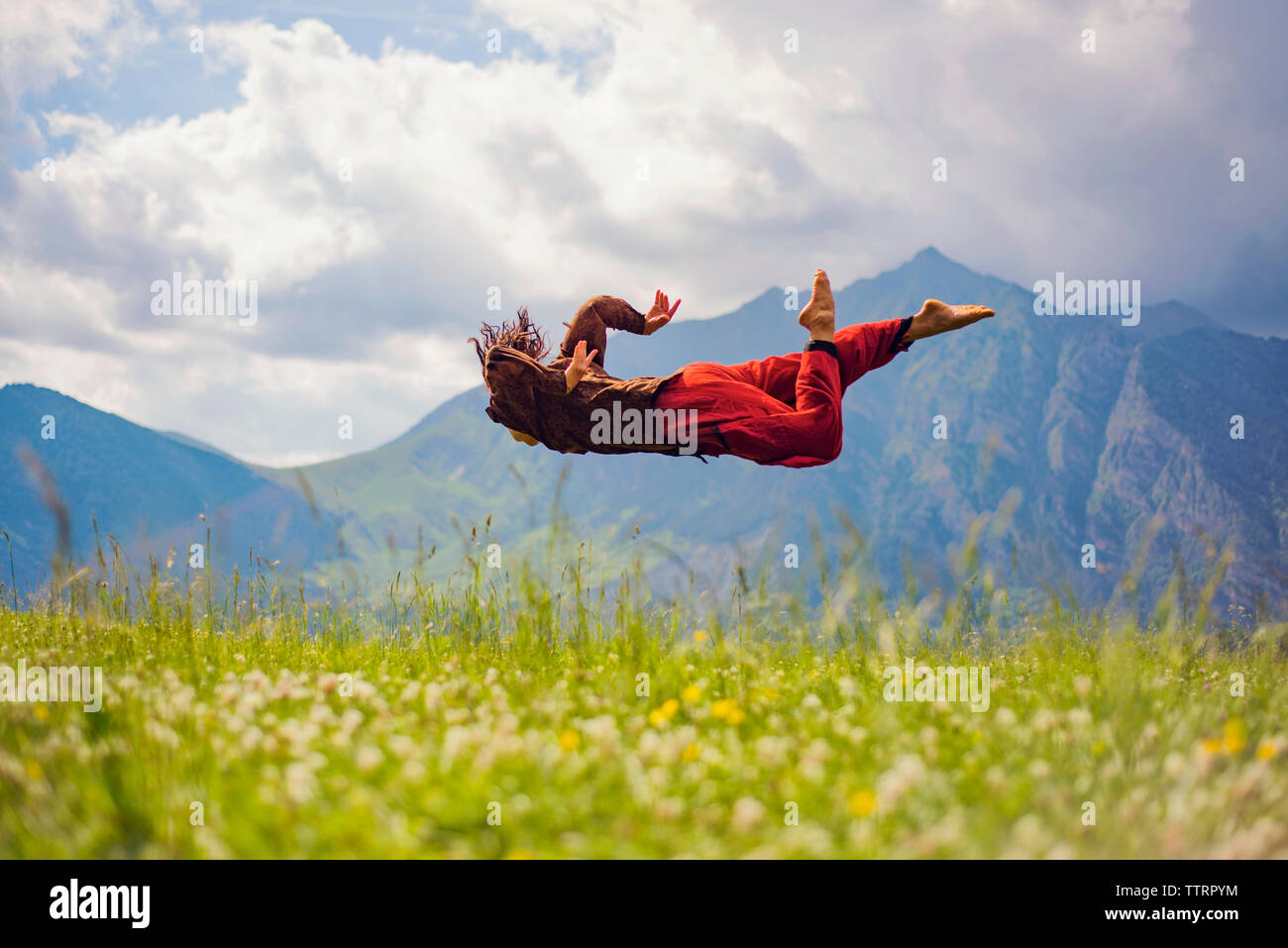 Frau in der Luft über Wiese gegen Berge Stockfoto