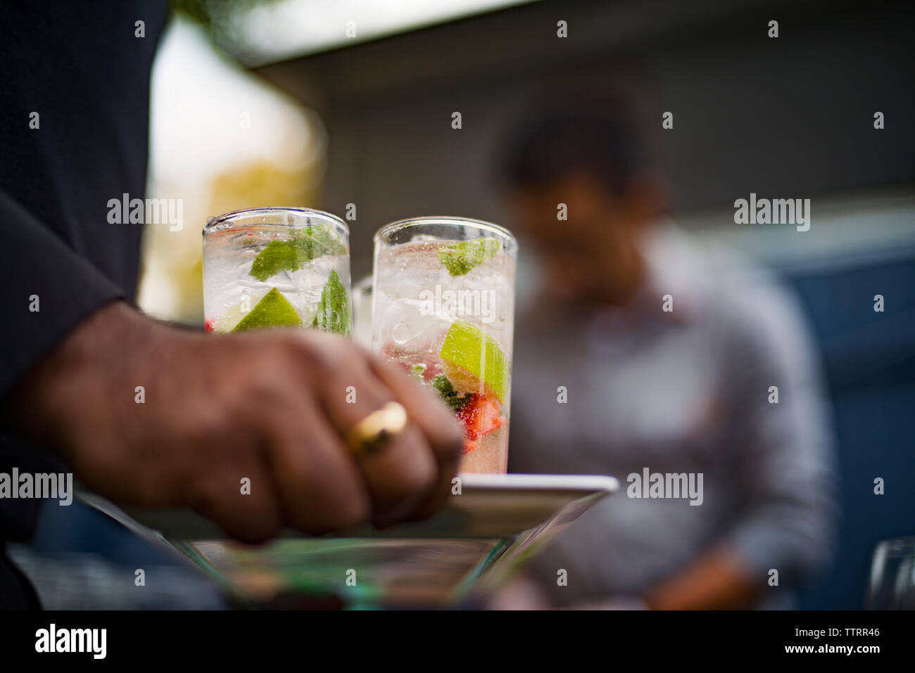 Zugeschnittenes Bild der Kellner Holding erfrischende Getränke in Fach bei Outdoor Restaurant Stockfoto