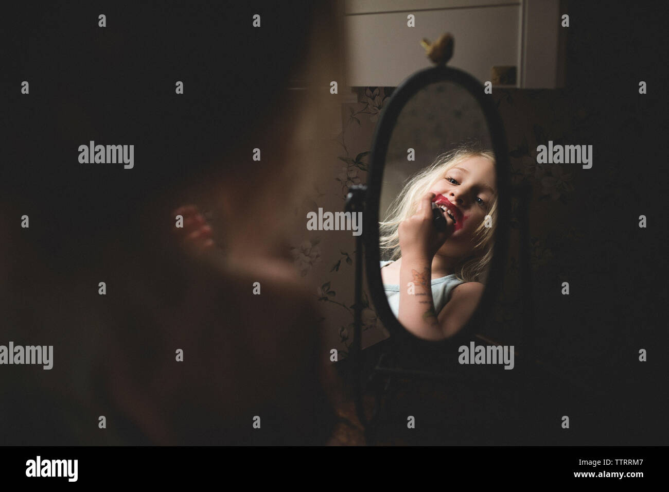 Mädchen Anwendung Lippenstift während im Spiegel zu Hause suchen Stockfoto