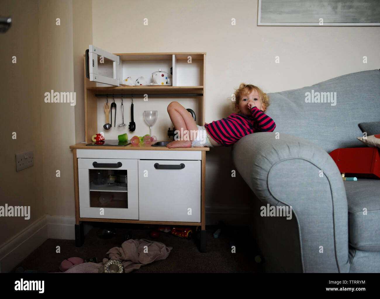 Portrait von Mädchen liegt auf dem Sofa und Spielzeug Küche Zähler Stockfoto