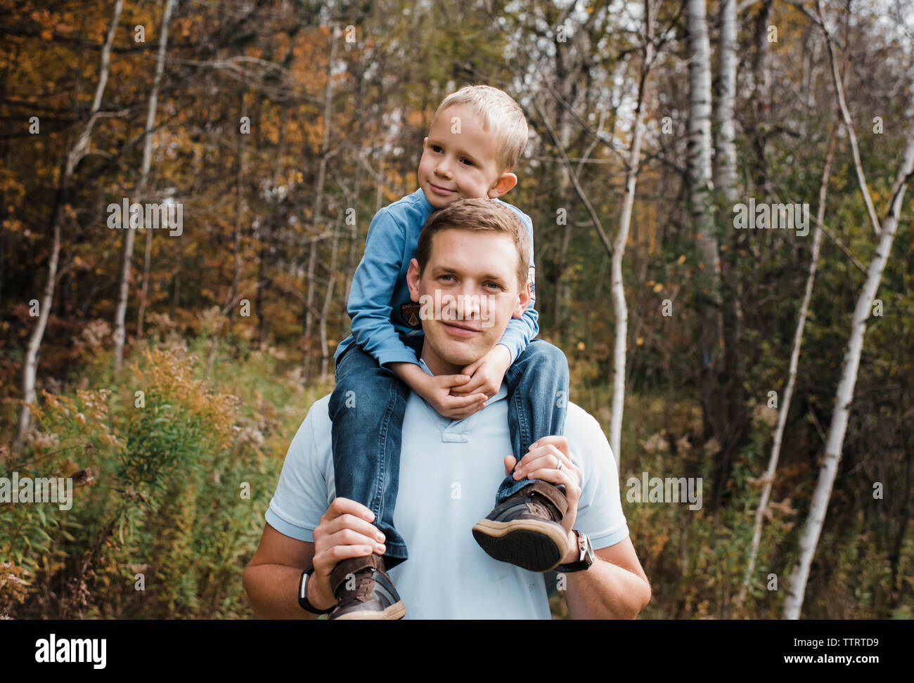 Portrait von Vater mit Sohn auf den Schultern beim Stehen in Wald Stockfoto