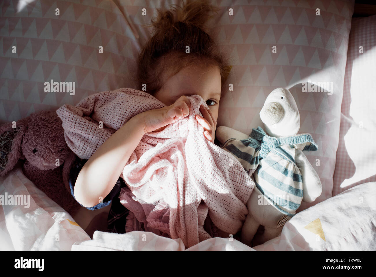 Overhead Portrait von cute girl für Auge mit textilen während auf Bett zu Hause liegen Stockfoto