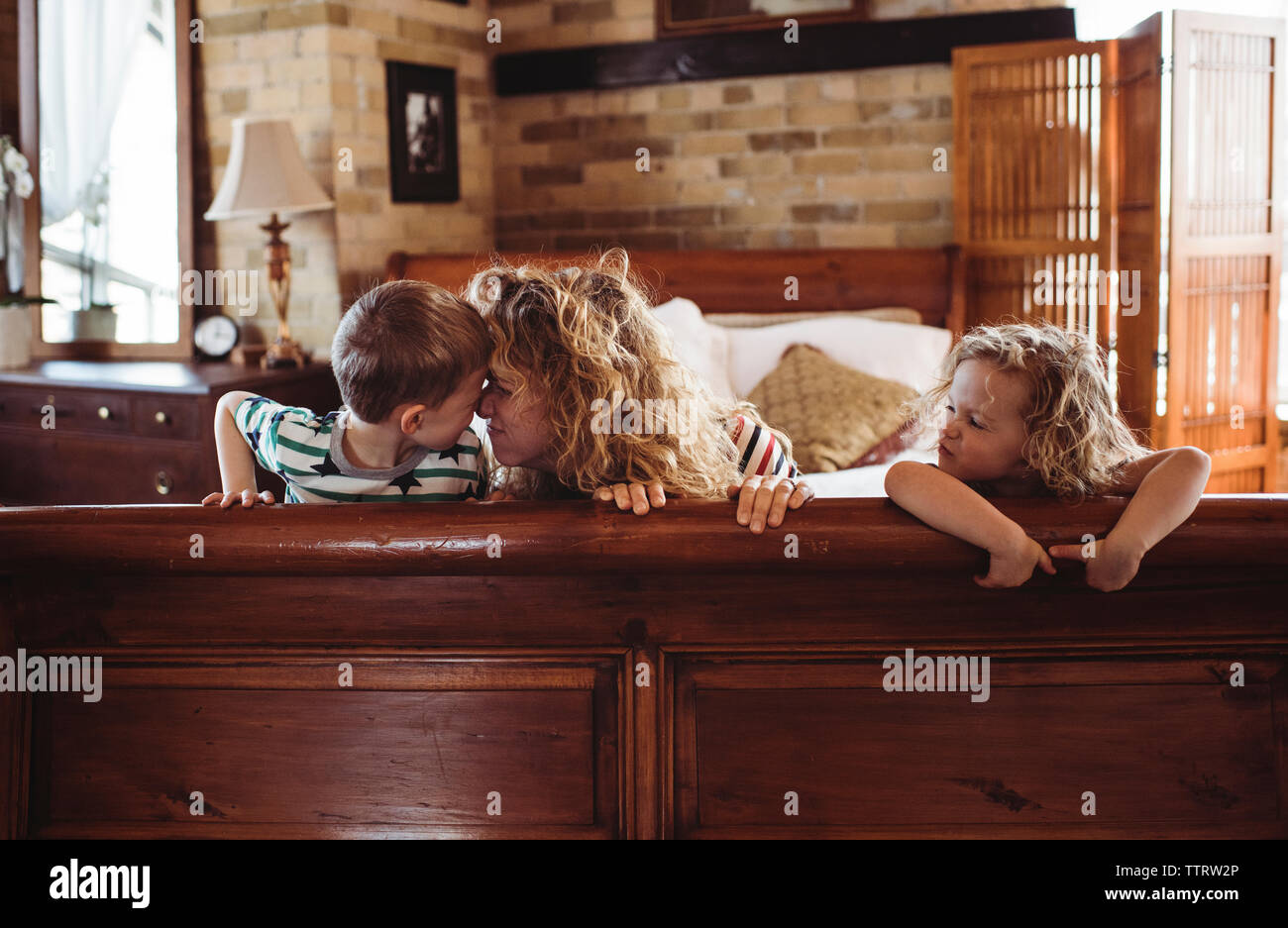Glückliche Mutter spielen mit den Kindern auf dem Bett zu Hause. Stockfoto
