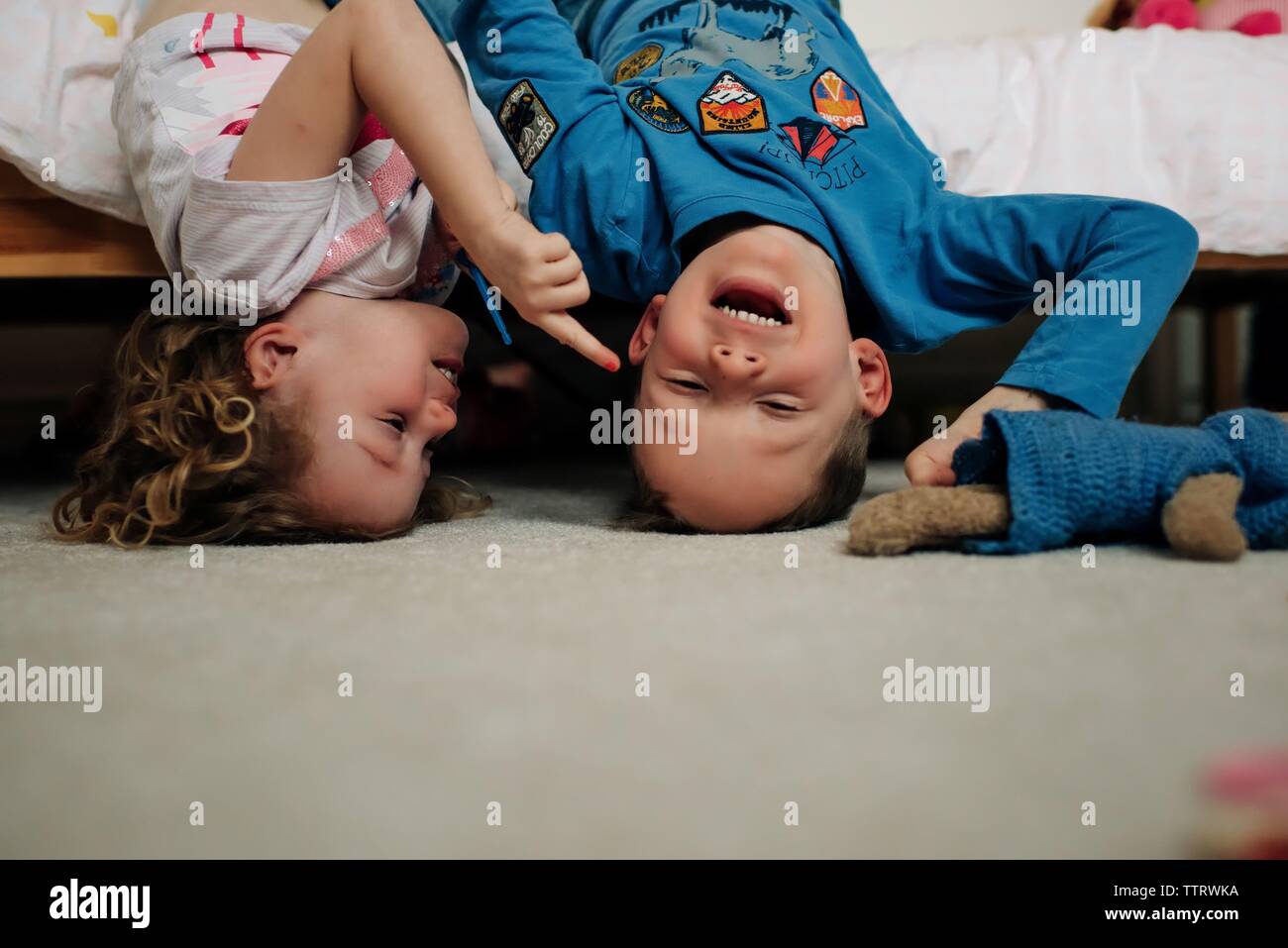 Jungen und Mädchen Geschwister zusammen lachen mit der Oberseite nach unten auf das Bett Stockfoto