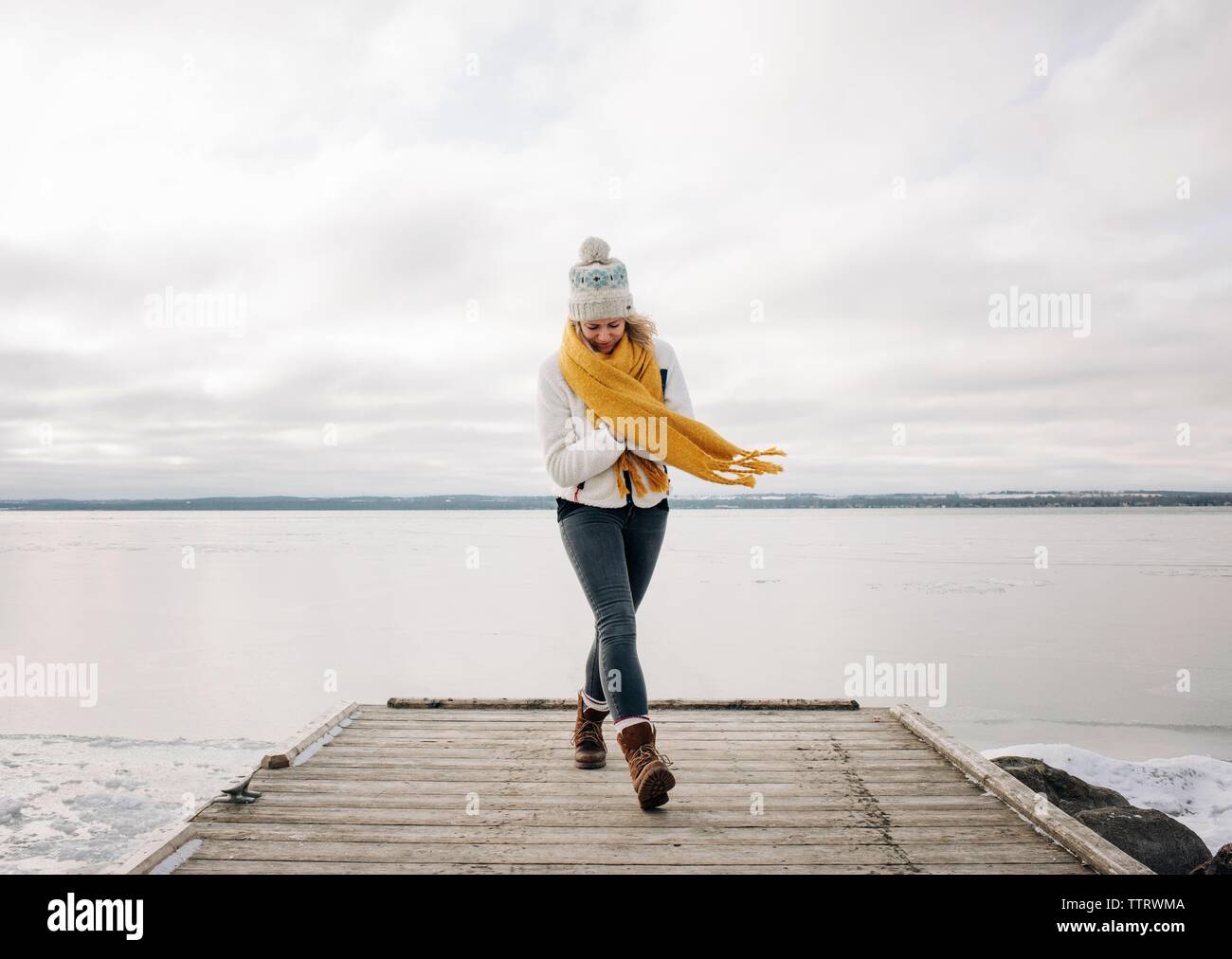 Frau zu Fuß auf den Pier am Strand mit See im Hintergrund Stockfoto