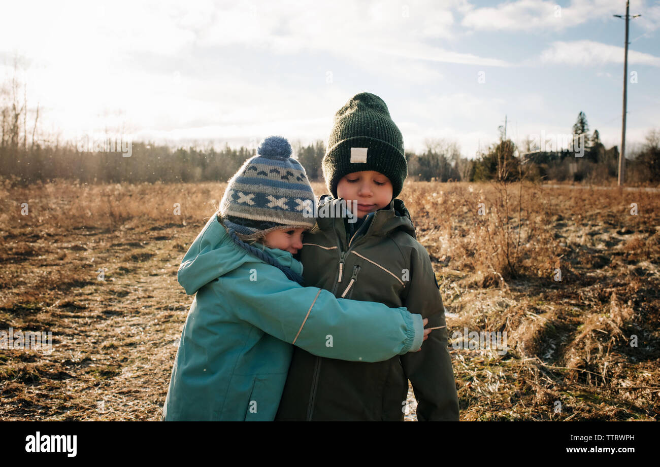 Bruder und Schwester umarmen Junge und Mädchen kuscheln im Freien spielen Stockfoto