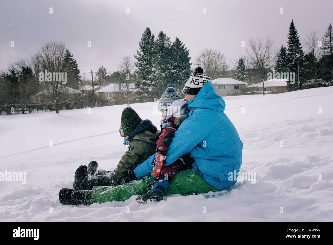 Vati Rodeln mit zwei Kinder im Schnee mit Spaß für die ganze Familie Stockfoto