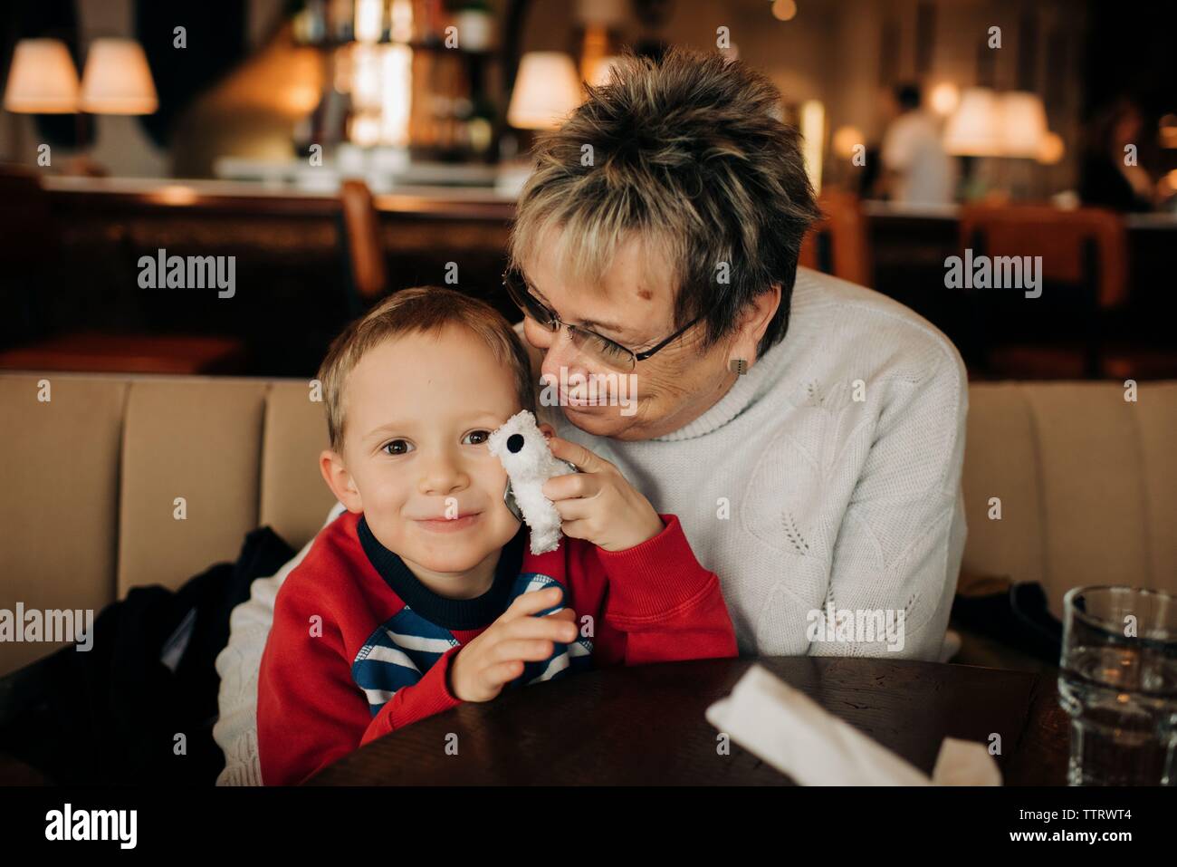 Junge blonde Junge saß mit grandma im Restaurant mit Spielzeug spielen Stockfoto