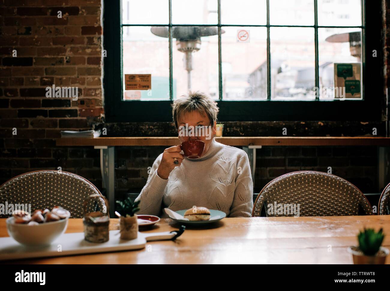 Frau Kaffee trinken in einem Café und essen Bagel Stockfoto