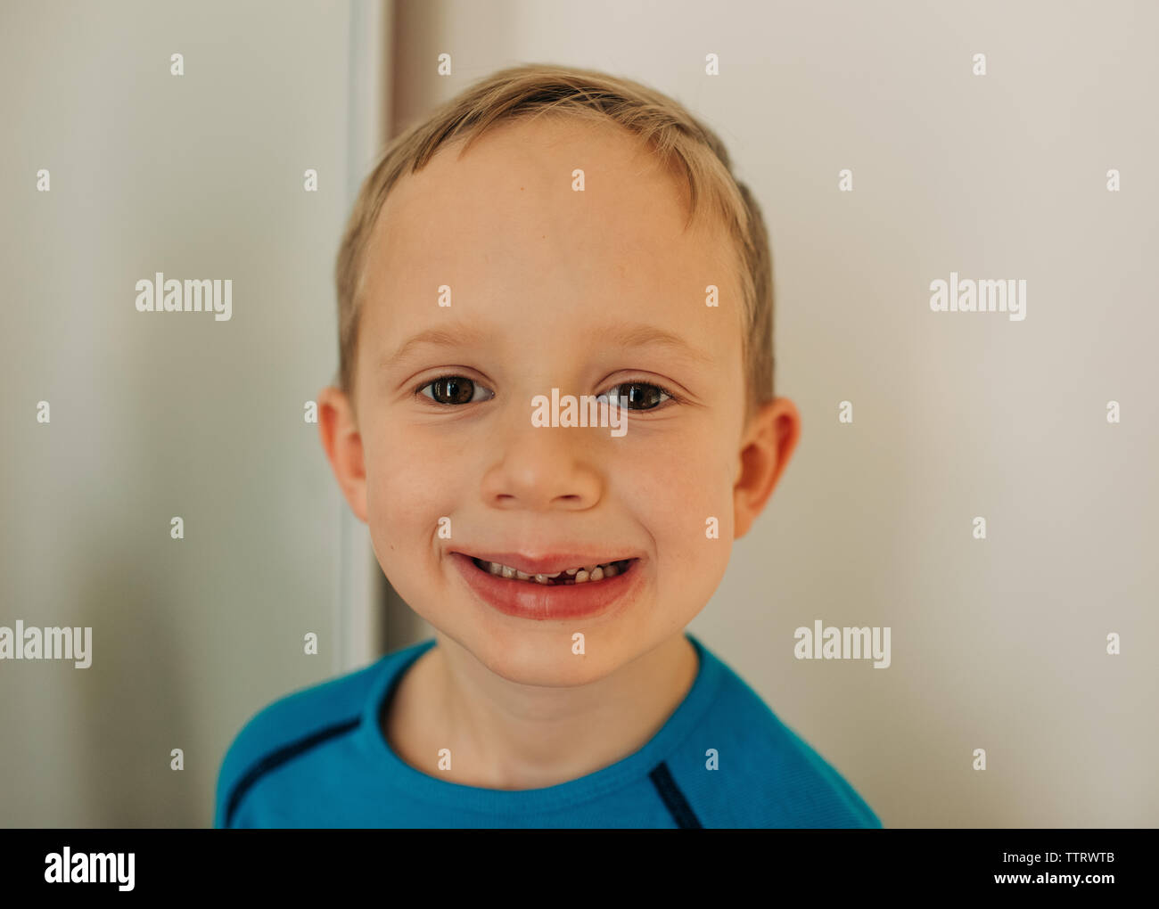 Junge blonde Junge mit fehlenden ersten Zahn Lächeln auf die Kamera schaut Stockfoto