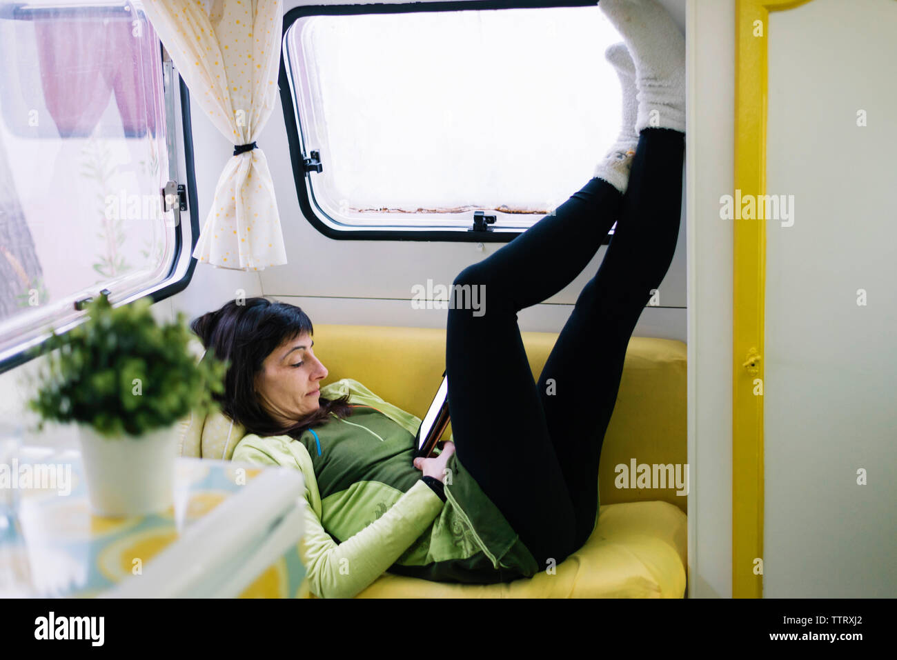 Seitenansicht des liegende Frau auf dem Sofa lesen ebook, Beine wand Stockfoto