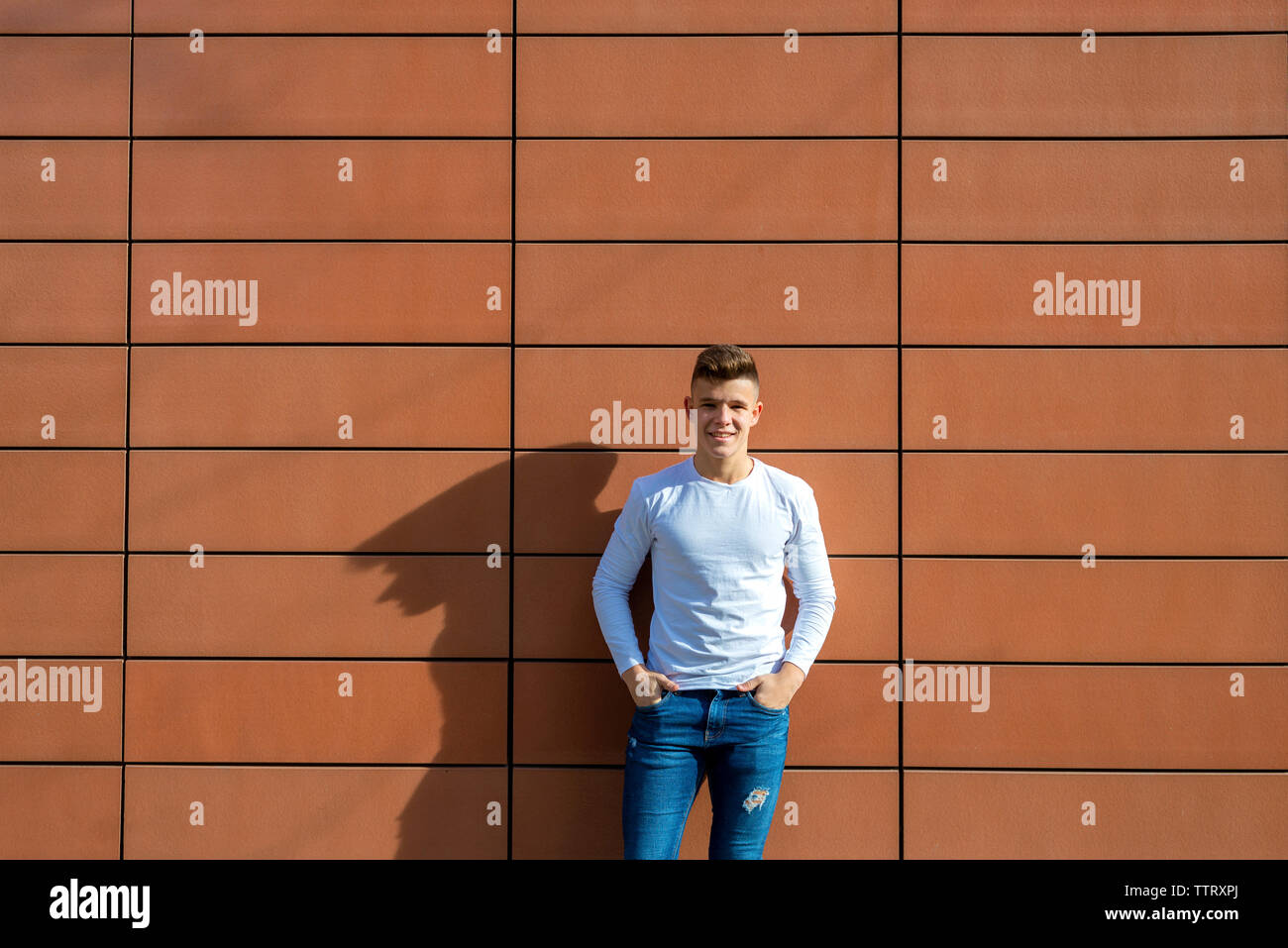 Vorderansicht junger Mann lehnte sich an die Wand, während Sie Kamera Stockfoto