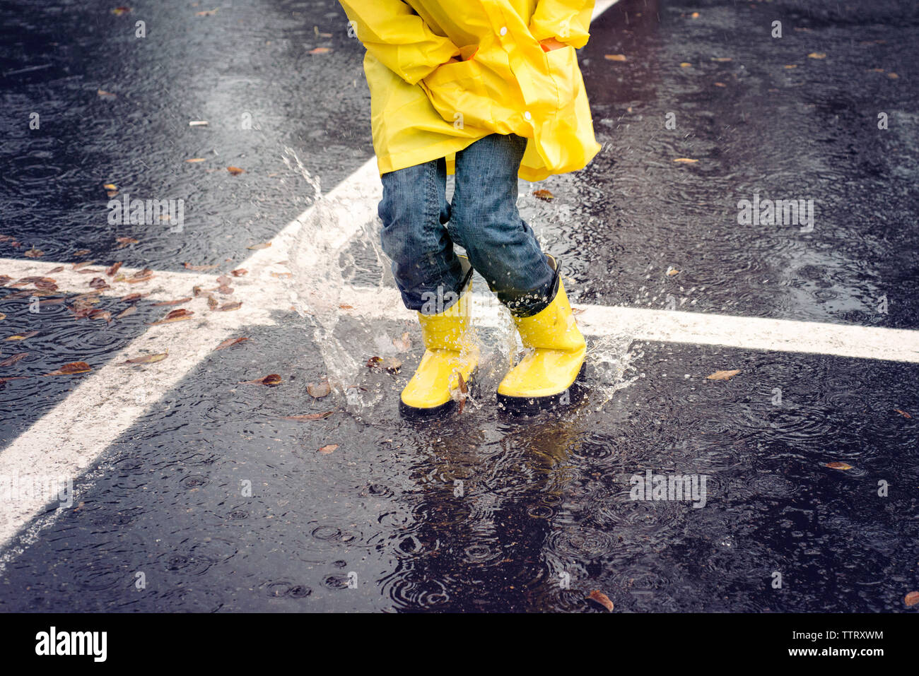 Low-Feld der Mädchen springen auf der Straße bei Regen Stockfoto