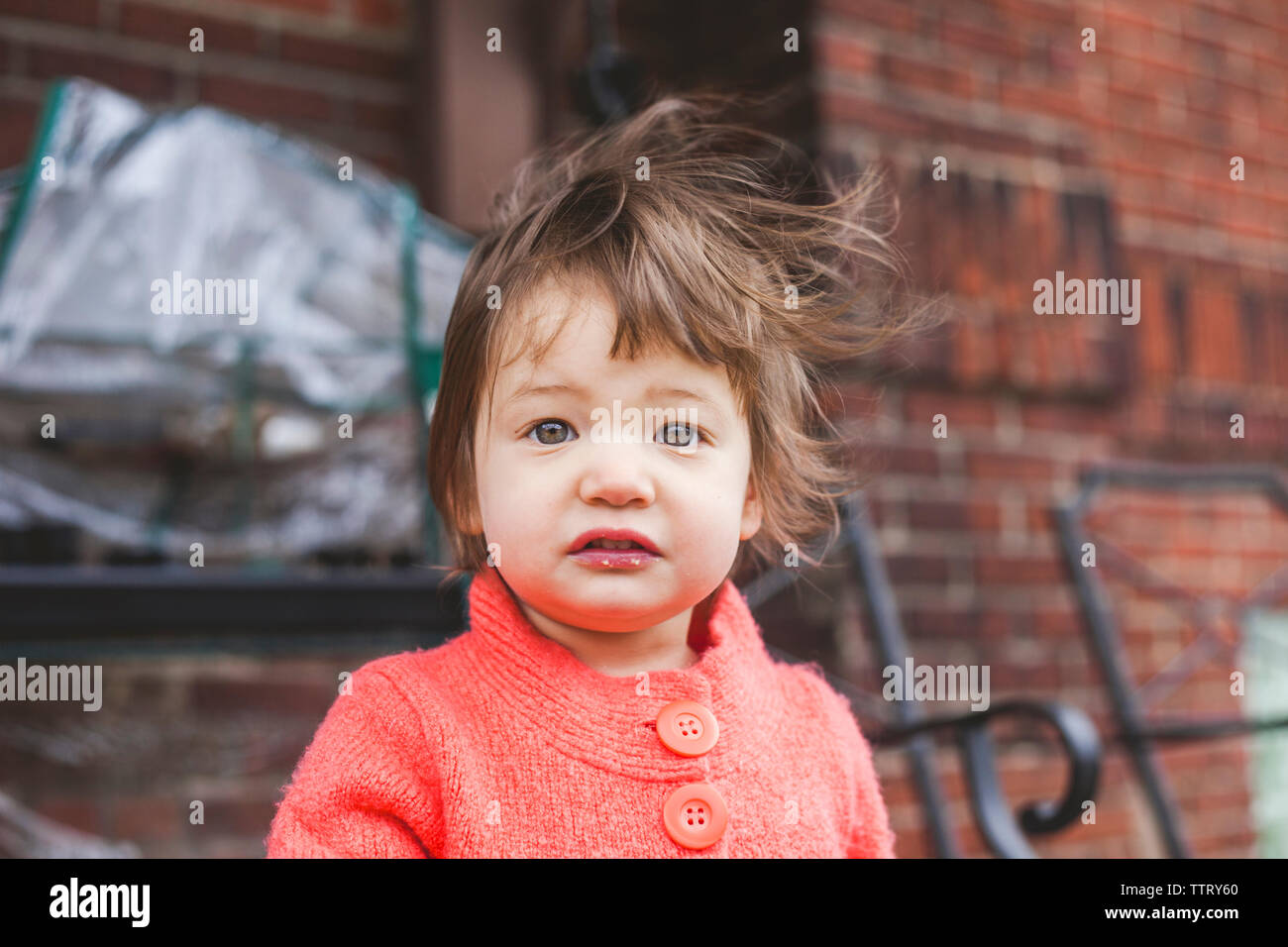 Close-up Portrait von niedlichen Baby Mädchen mit unordentlichen Haar gegen Mauer Stockfoto