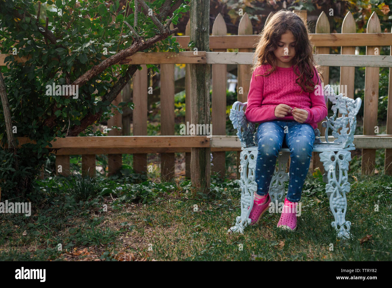 Trauriges Mädchen sitzen auf Stuhl in Hof Stockfoto