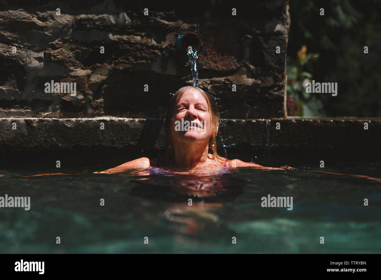 Frau mit geschlossenen Augen schwimmen im Pool bei der Tourist Resort während der sonnigen Tag Stockfoto