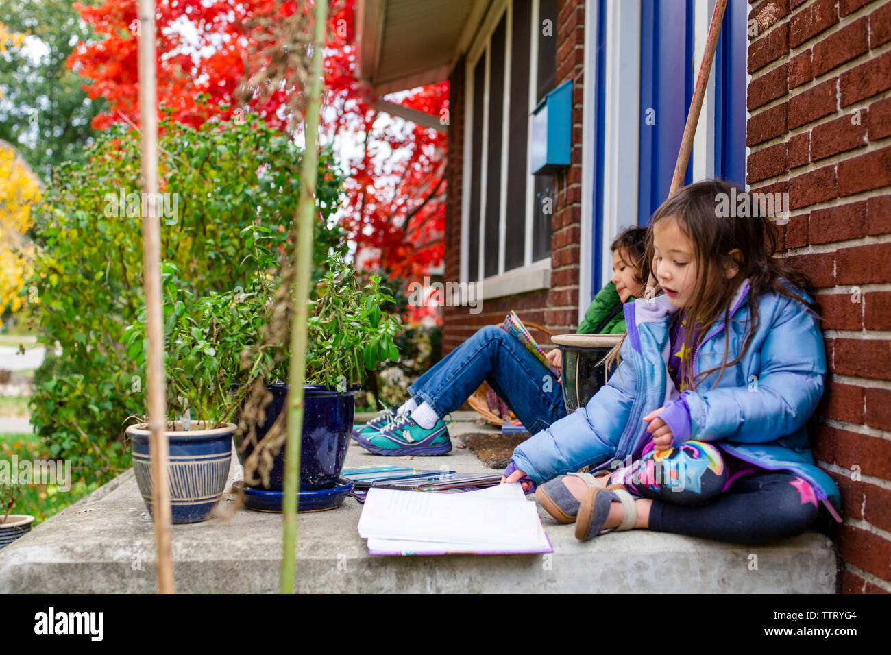 Zwei Kinder lesen gemeinsam draußen auf ihren vorderen Stoop Stockfoto