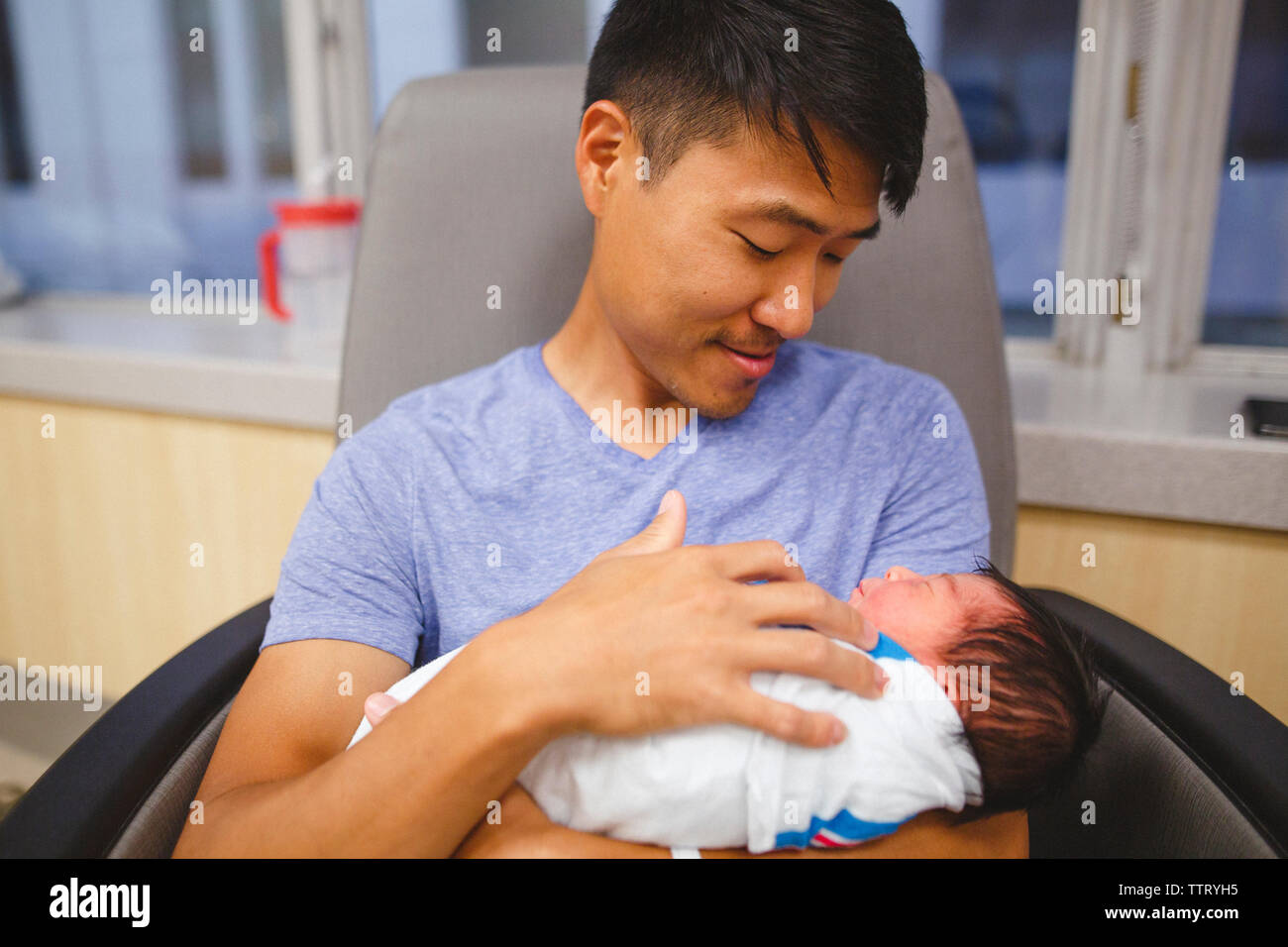 Ein stolzer neuer Vater blickt adoringly an seiner neugeborenen Tochter, schaukelnd Stockfoto