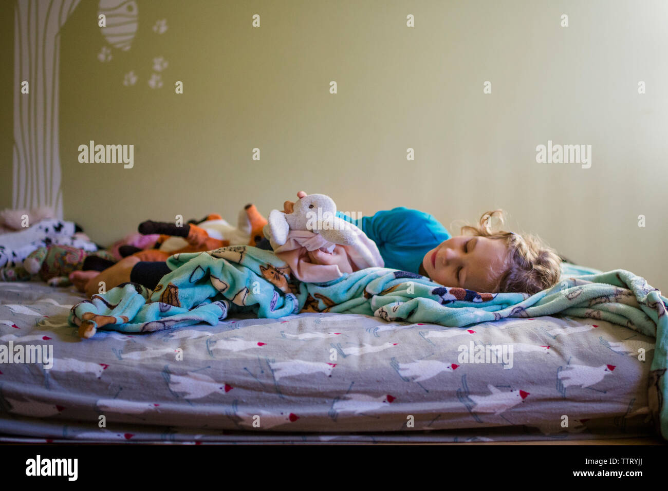 Ein glückliches Mädchen im Bett kuschelt mit ihren Stofftieren Stockfoto