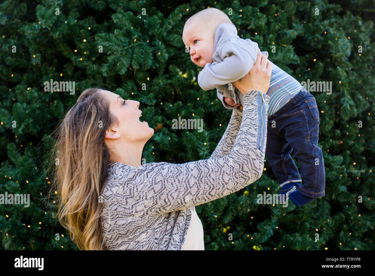 Eine lächelnde Mutter zärtlich hebt Ihre baby boy in die Luft Stockfoto